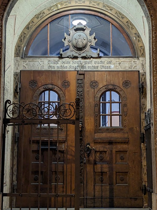 »Stähl' deine Kraft, greif wacker an! Ein rechter Knab', ein rechter Mann!« – Motto über einer Schule in München-Laim (2023)