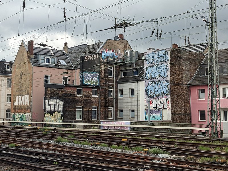Wenn man mit dem Zug nach Köln reinfährt, kommt man kurz vor dem Hauptbahnhof an diesen rückwärtigen Hausfassaden vorbei. Sah schon Ende der 1980er heruntergekommen aus; das Grafitti macht's nicht besser (2025).